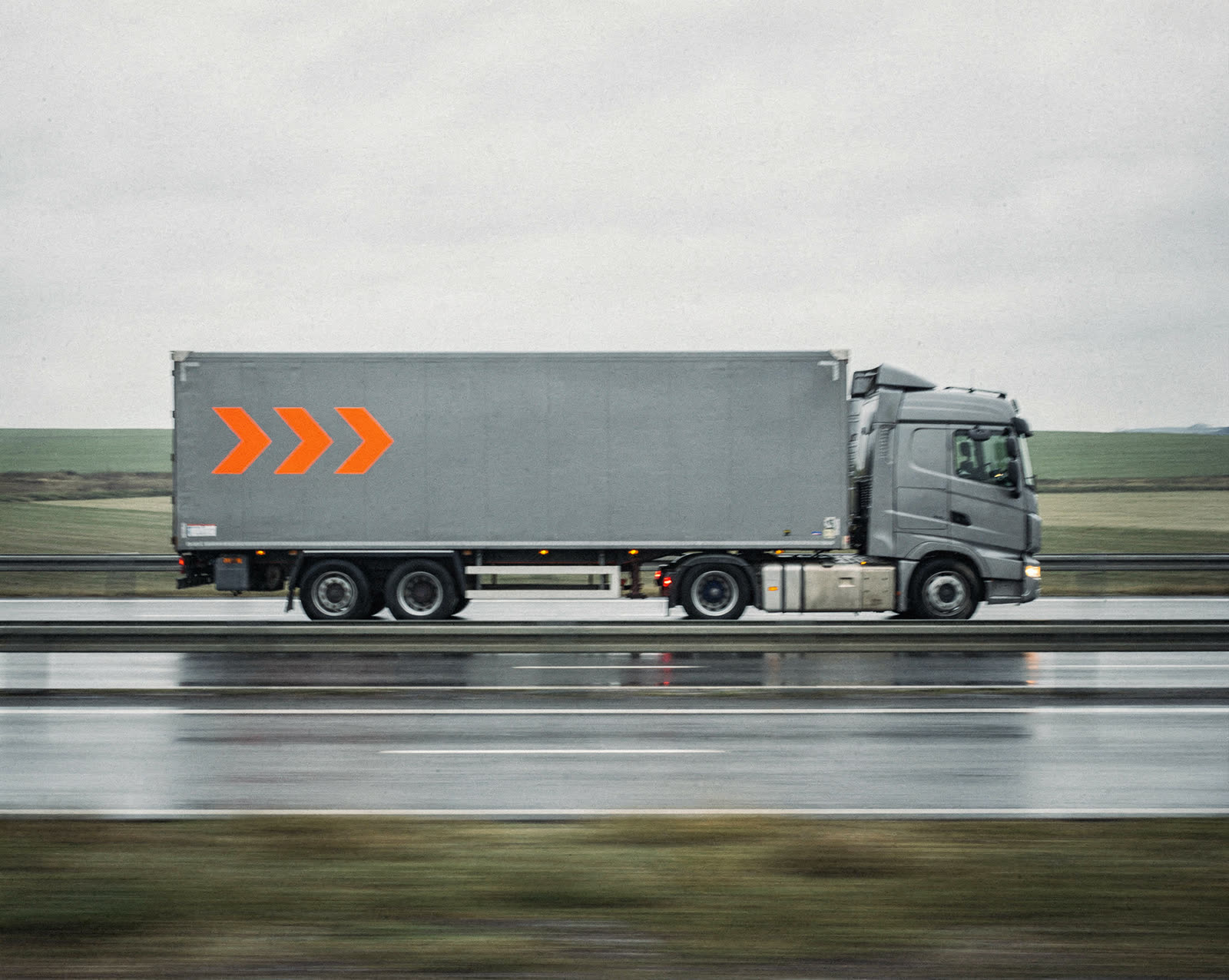 A graphite Vektor truck with orange chevrons driving along a motorway